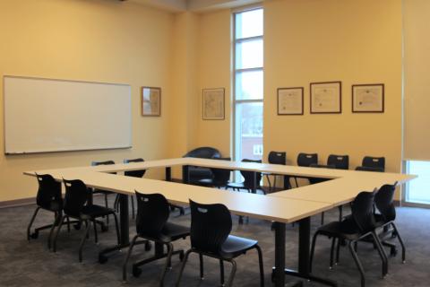 Bright, large room with a square of tables set in the middle, surrounded by chairs.