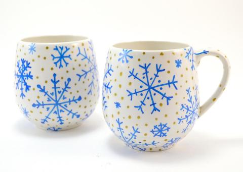 two mugs depicting winter scenes decorated with snowflakes