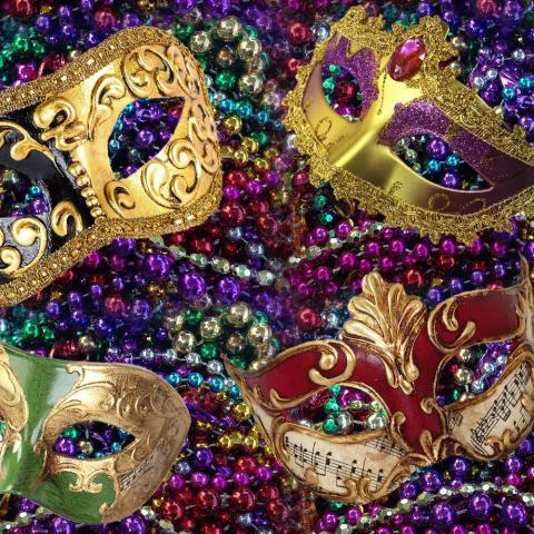 Picture of gaily decorated masks sit atop pile of multi-colored beads