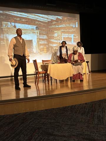 Four African American actors on stage with screen in the background.
