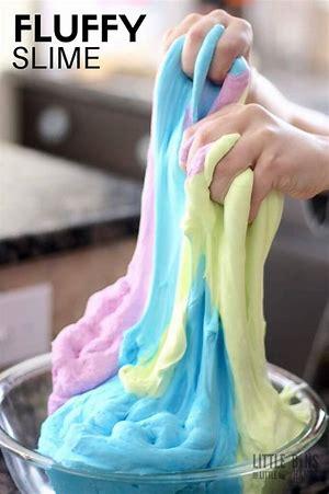 hands pulling slime in pink, blue and yellow from a clear bowl