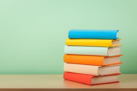 Books in red, orange, yellow, blue, green with a green background.