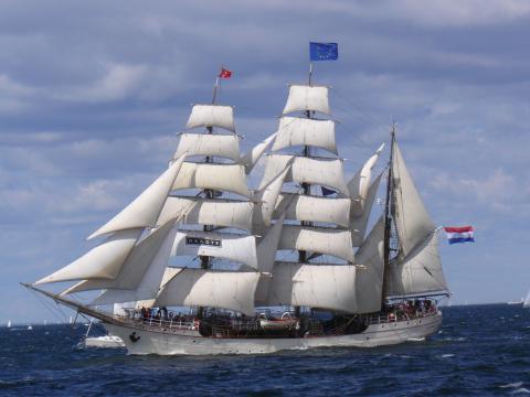 A sailboat with white masts and a bright blue sky behind it.