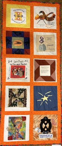 a quilt with a burnt orange background with 10 different squares celebrating African spirit