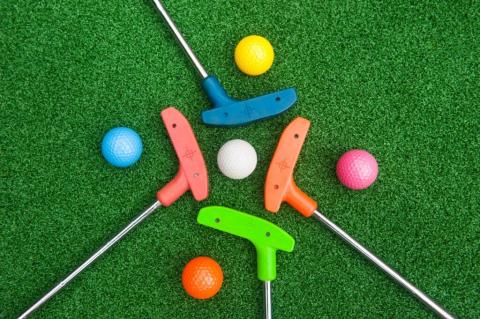 Green, orange, red, blue mini golf clubs and golf balls.