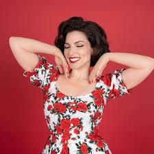 Vanessa Racci in a red floral dress with a red background.