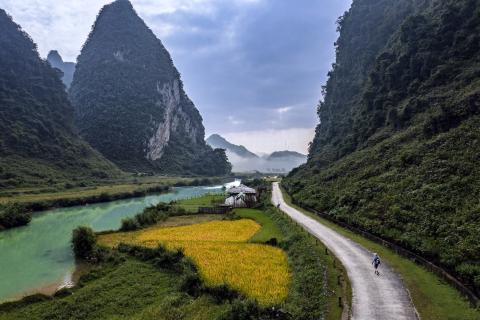 Green mountains with blue sky, yellow ground and a winding road.