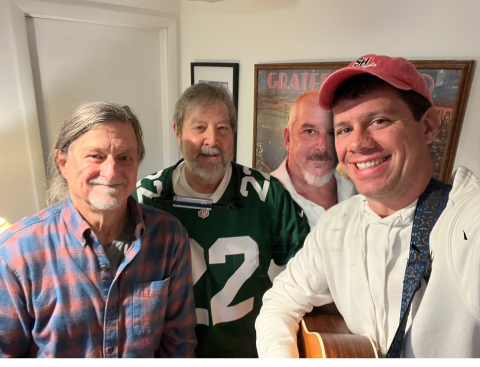 Four guys taking a picture with a white background.