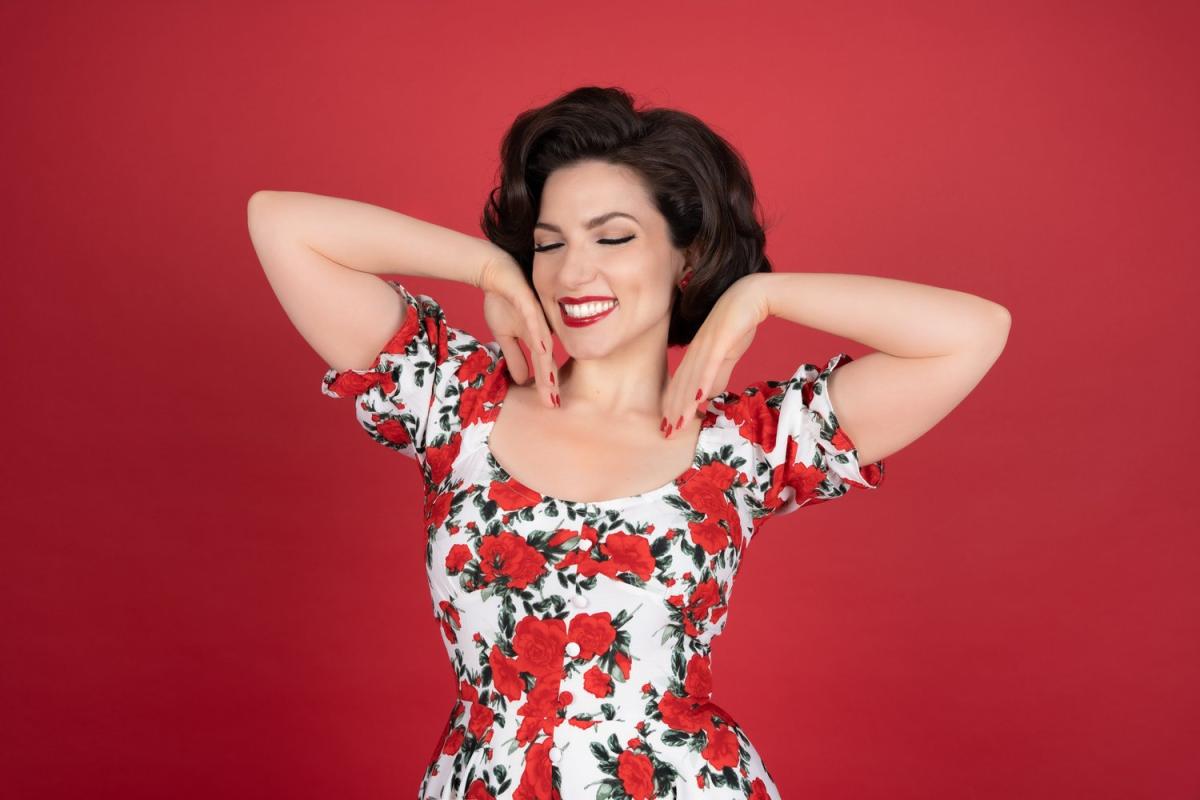 Performer in a floral dress against a red backdrop