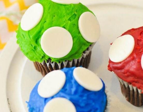 three brightly frosted cupcakes topped with candy discs.