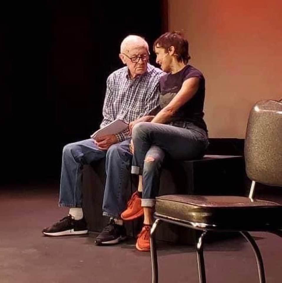 Father and daughter sitting and chatting with a red and black background.