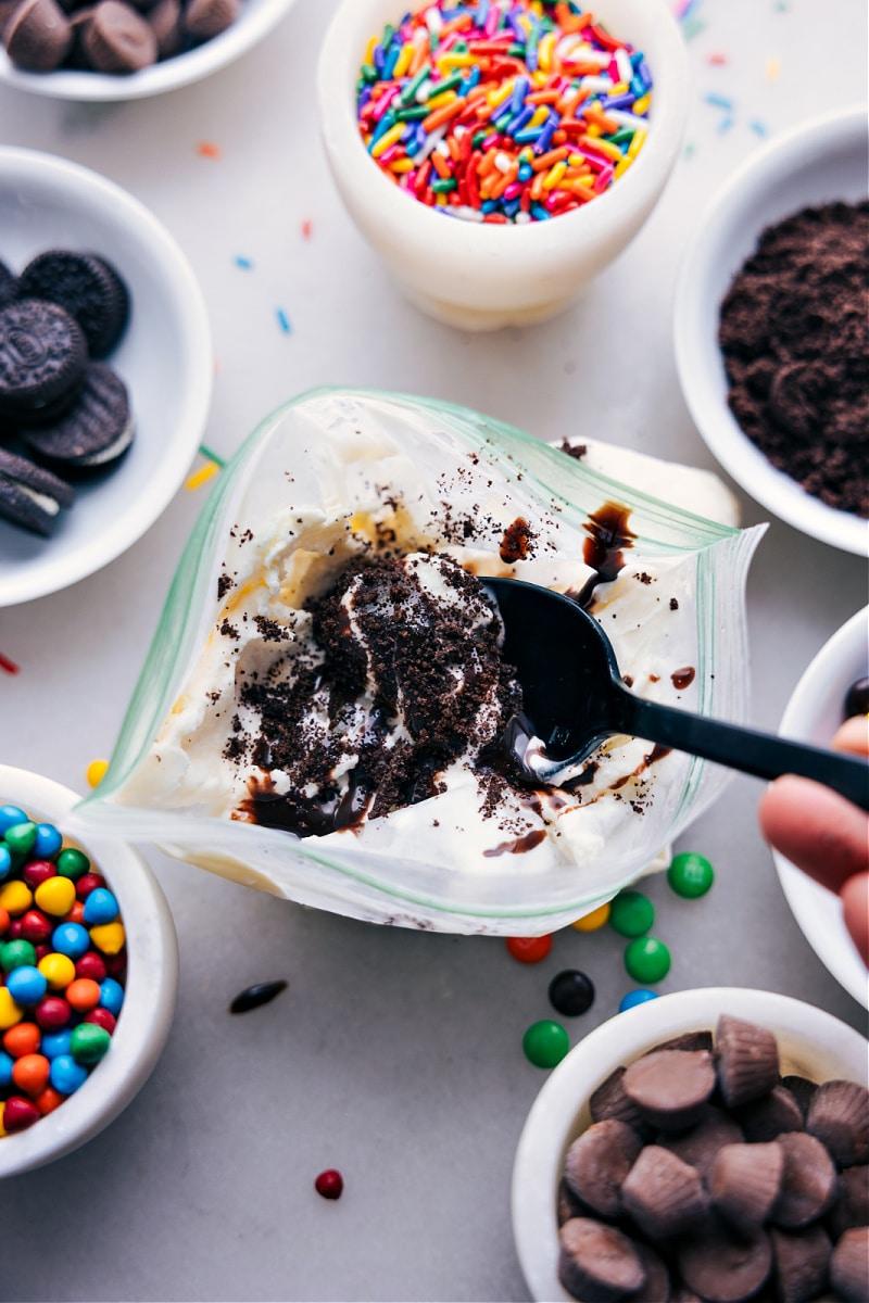 vanilla ice cream in a bag surrounded by cups of various toppings