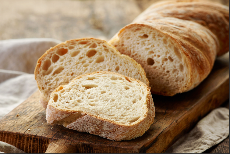 3 thick slices of Italian bread on a dark brown cutting board