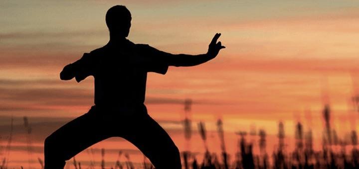 A person doing Qigong with the sunset in the background.