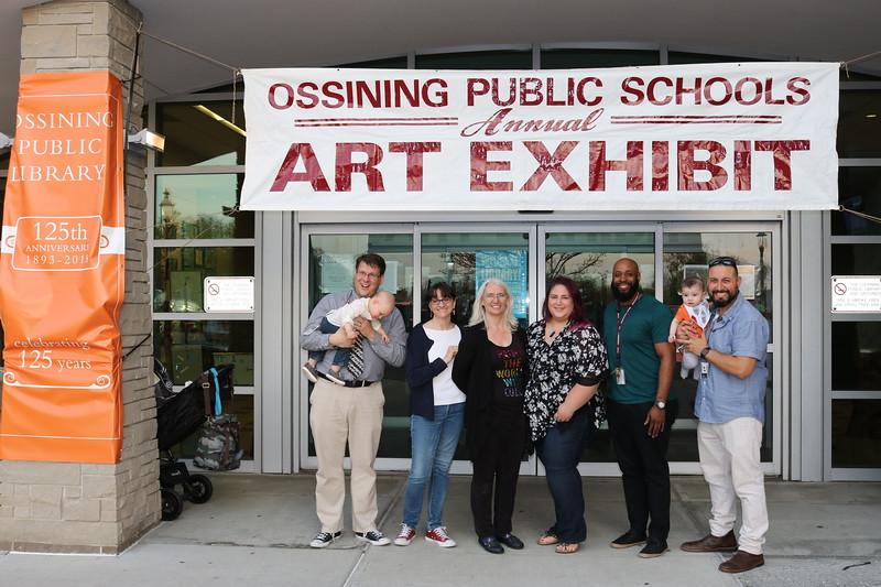 People standing underneath white and maroon banner.