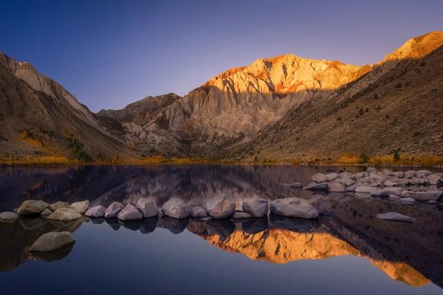 Mountains with a blue sky and reflection in water.