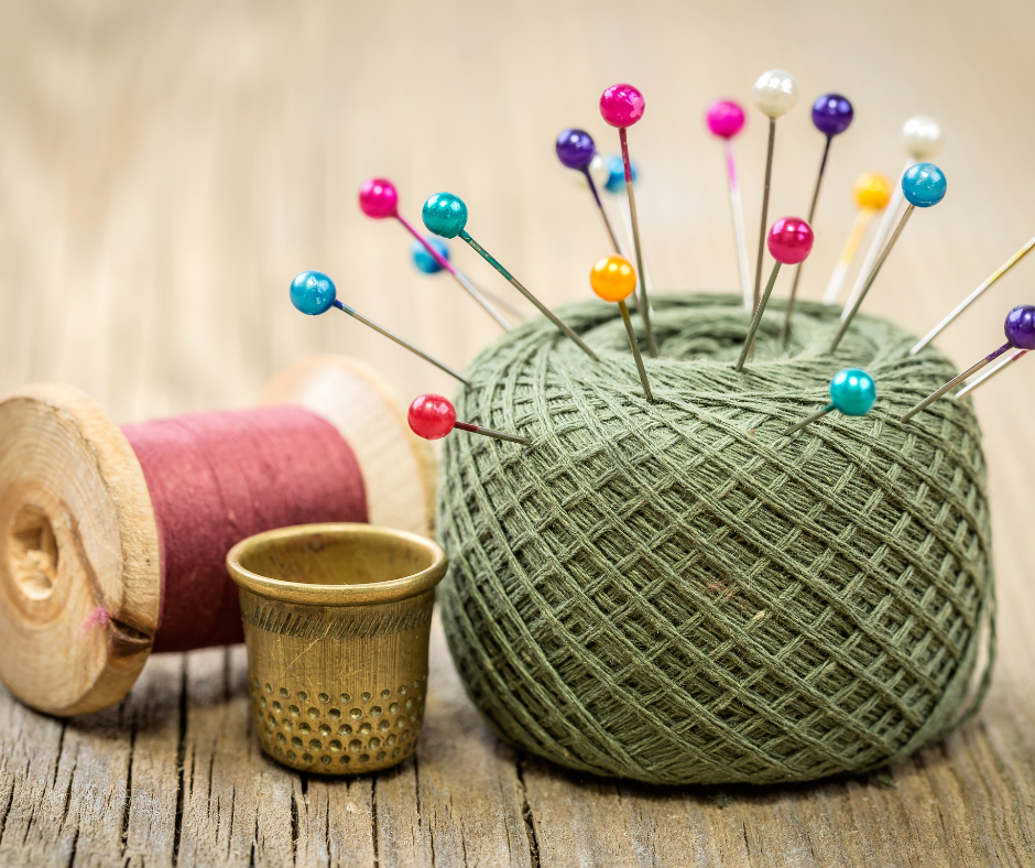 Sewing needles and green and pink thread.